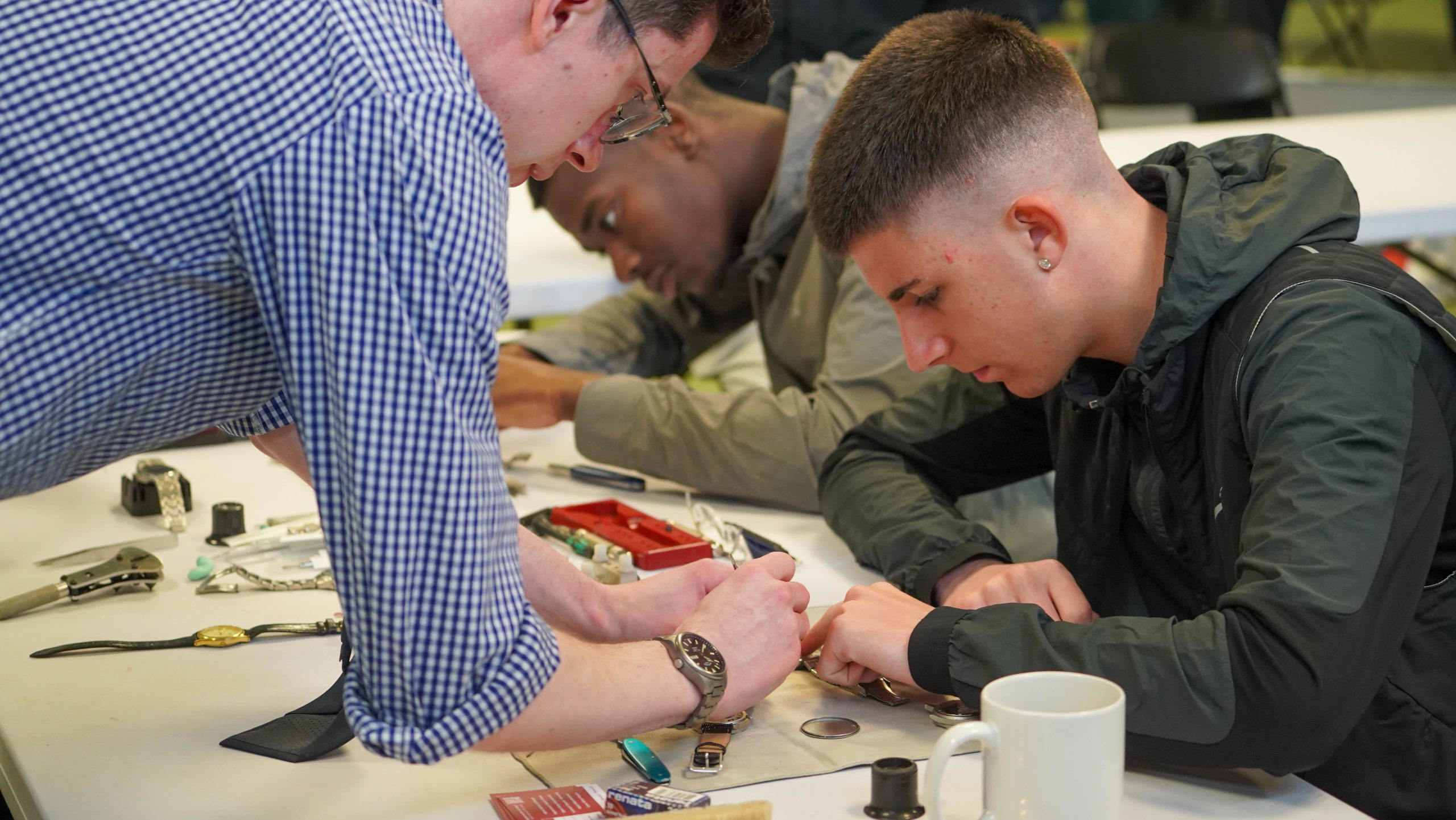 A young man being shown how to fix a watch by a Timpsons employee