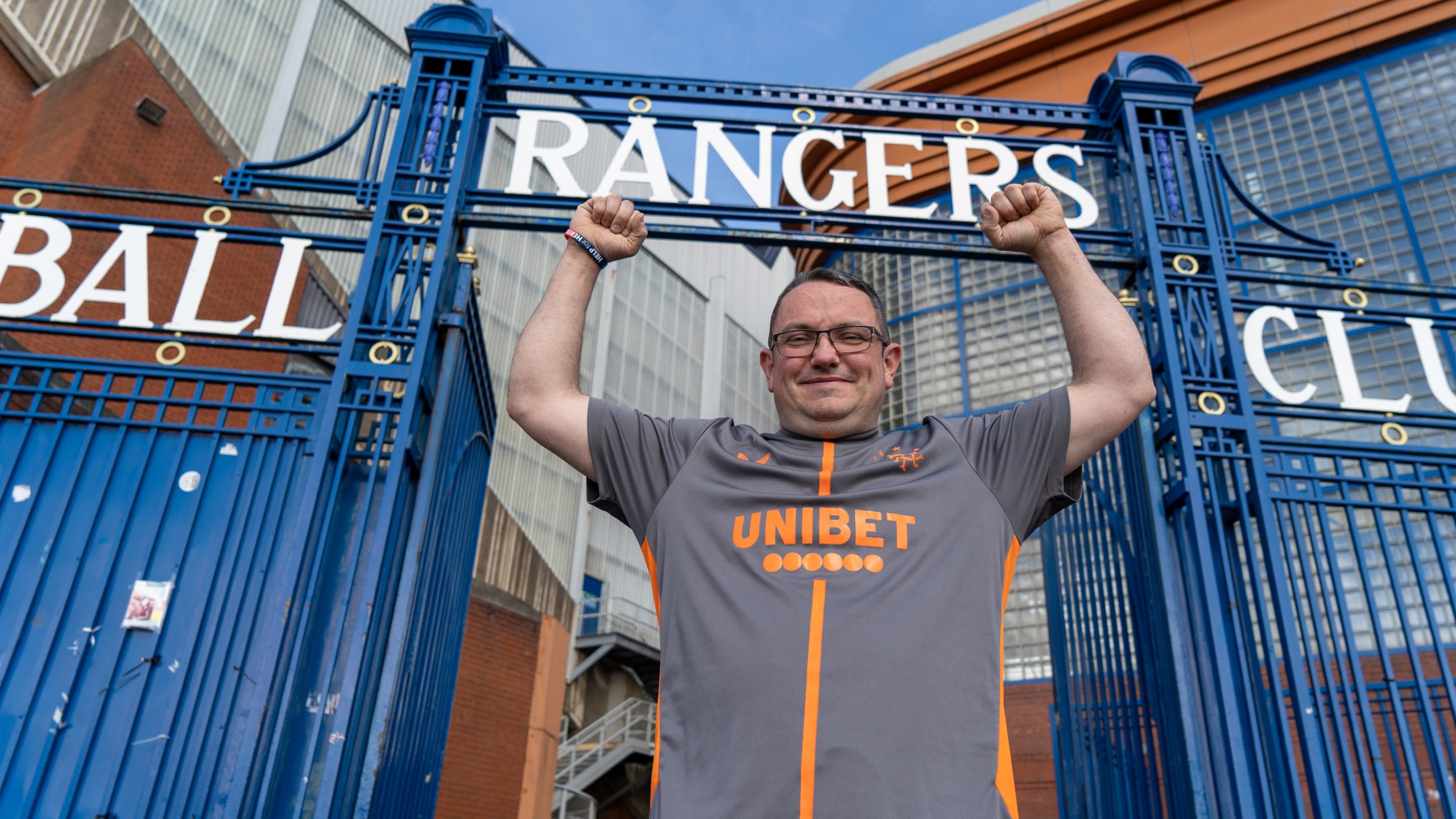 man standing under gate with words Rangers above