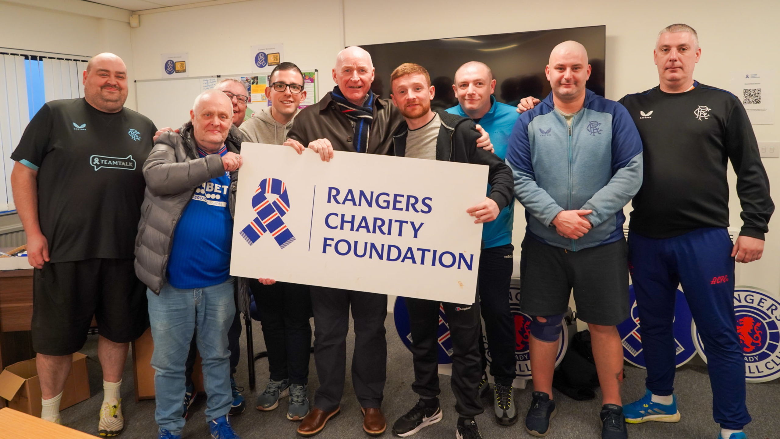 A group of men standing next to former Rangers player John Brown