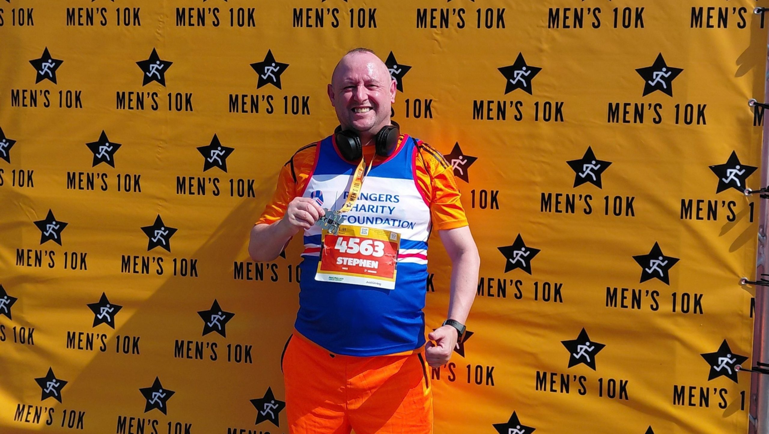 man in rangers running top with medal in front of 10K backdrop