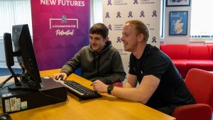 Staff help a young person at a computer in the Ibrox Community Hub