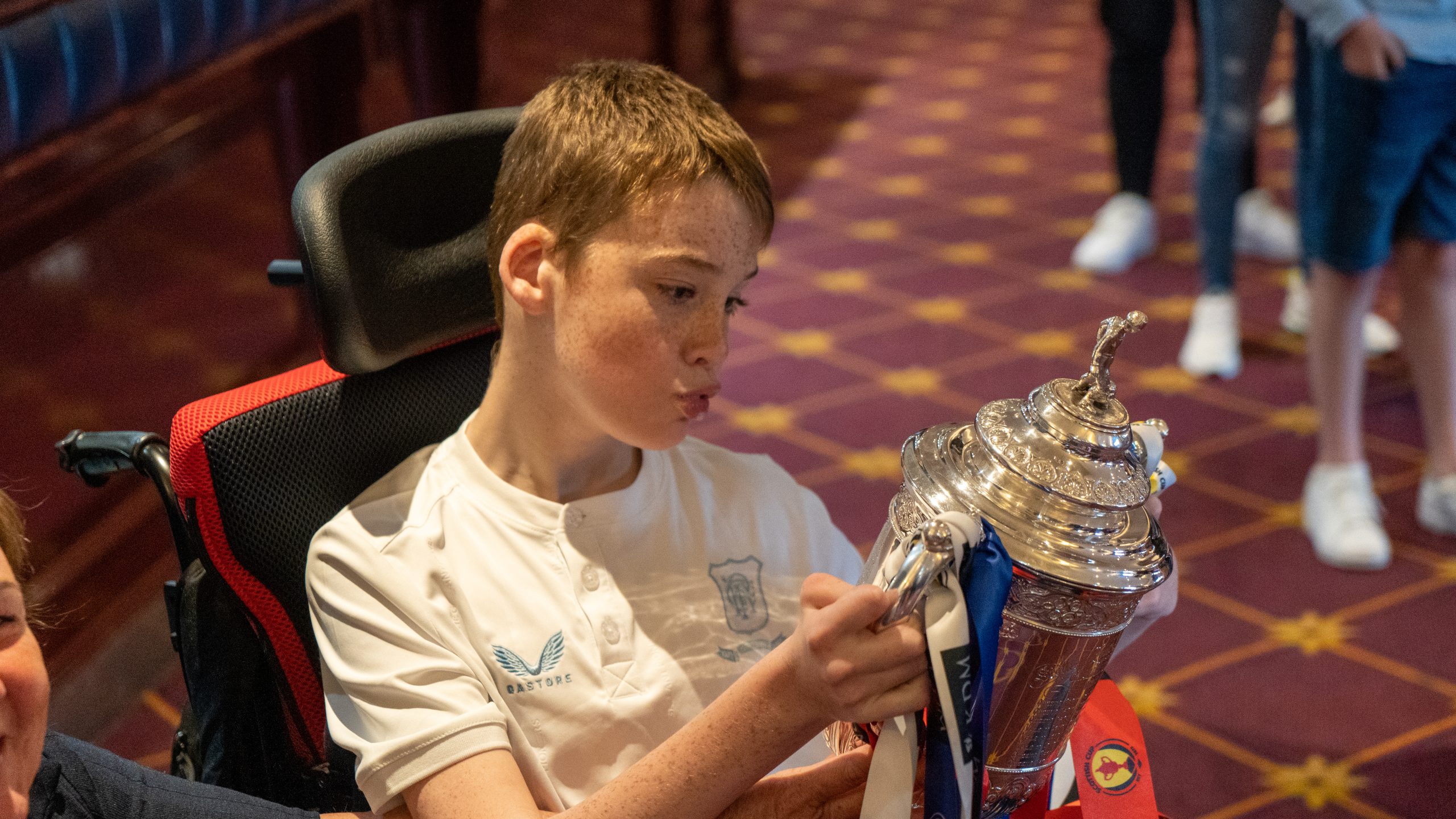 Boy in wheelchair holding trophy