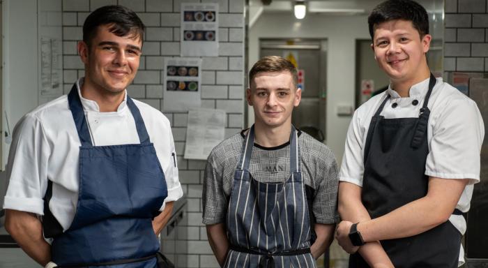 Three chefs standing in a kitchen