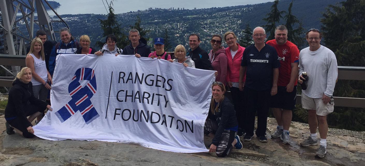 16 people holding Rangers Charity Foundation Flag