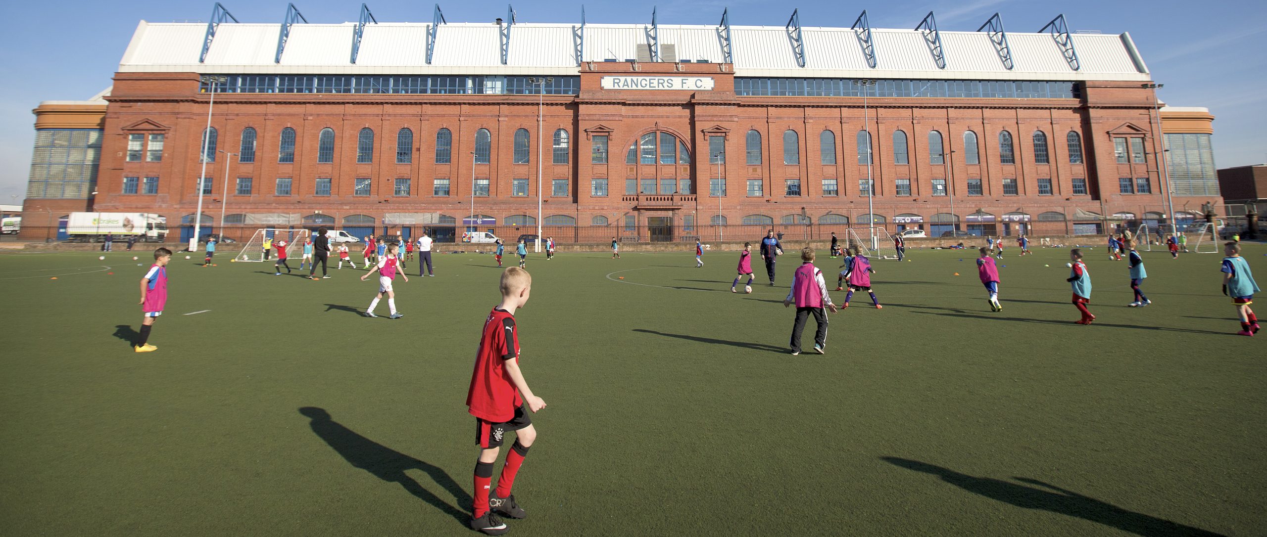 2 teams playing football with Ibrox Stadium in background