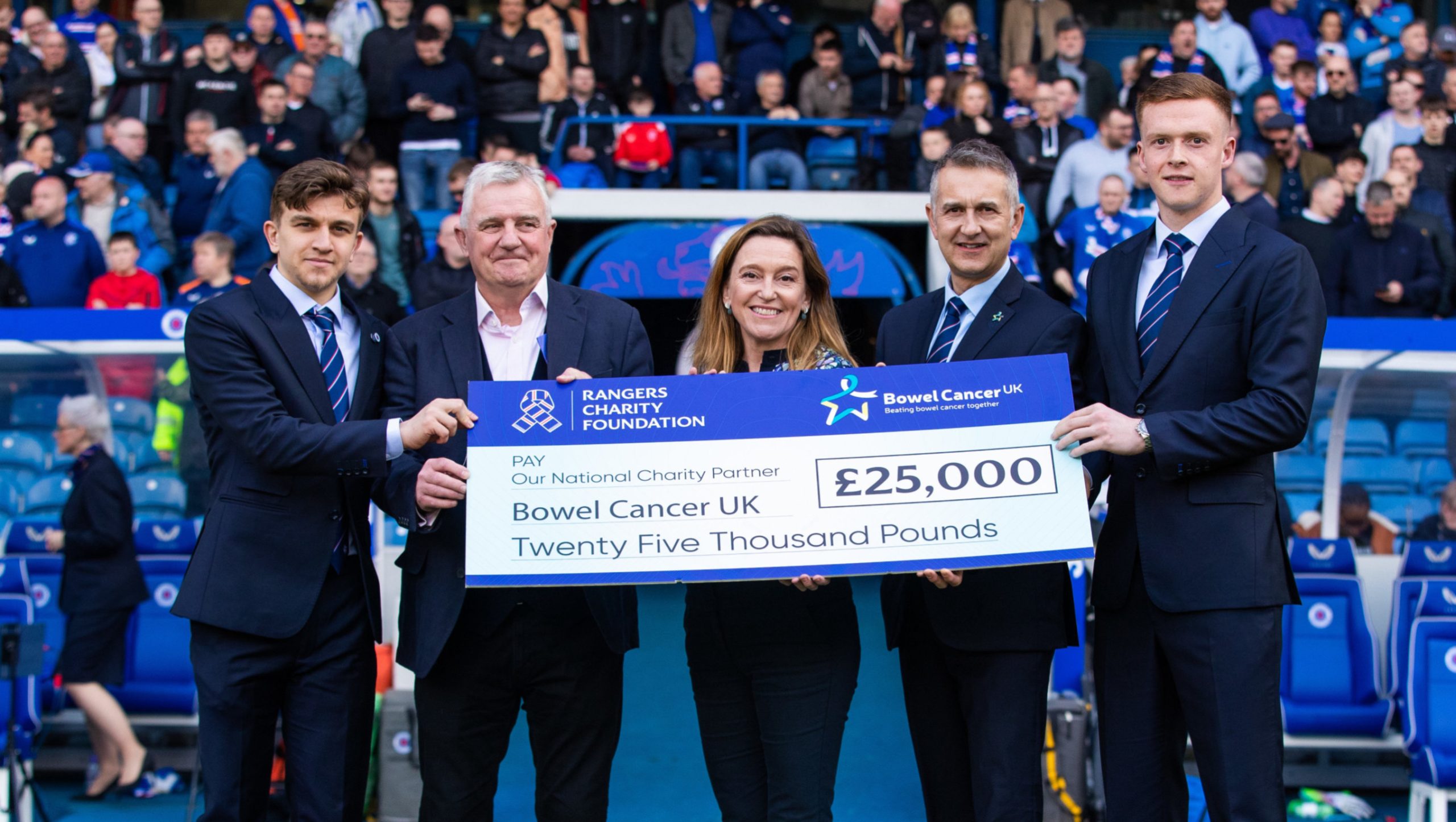 5 people in Ibrox stadium holding Bowel Cancer Cheque