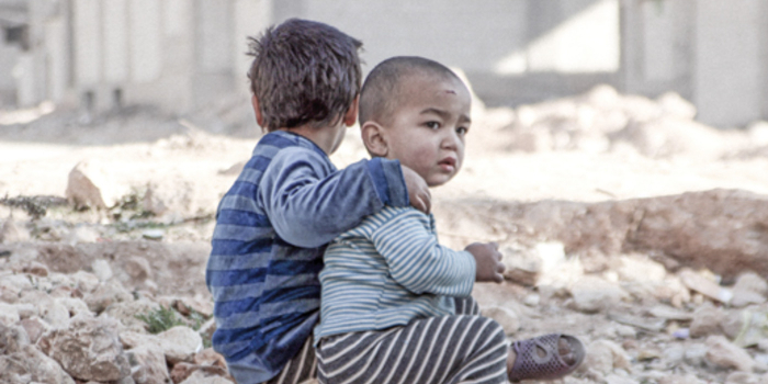 2 boys sitting in rubble