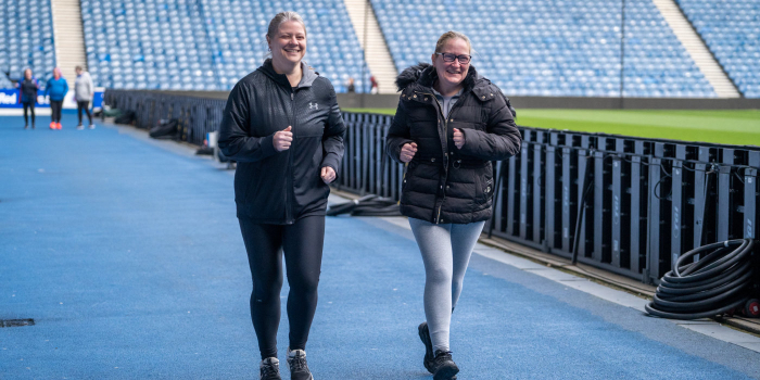 Two women running round the track at Ibrox