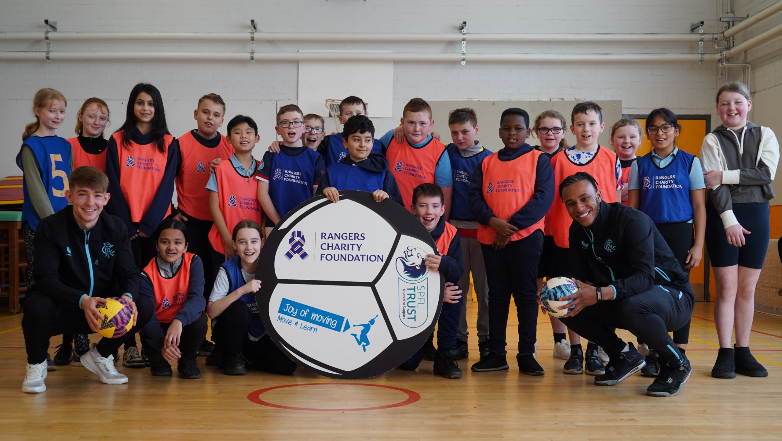 Rangers players Zak Lovelace and Robbie Fraser in a group photo with school pupils.