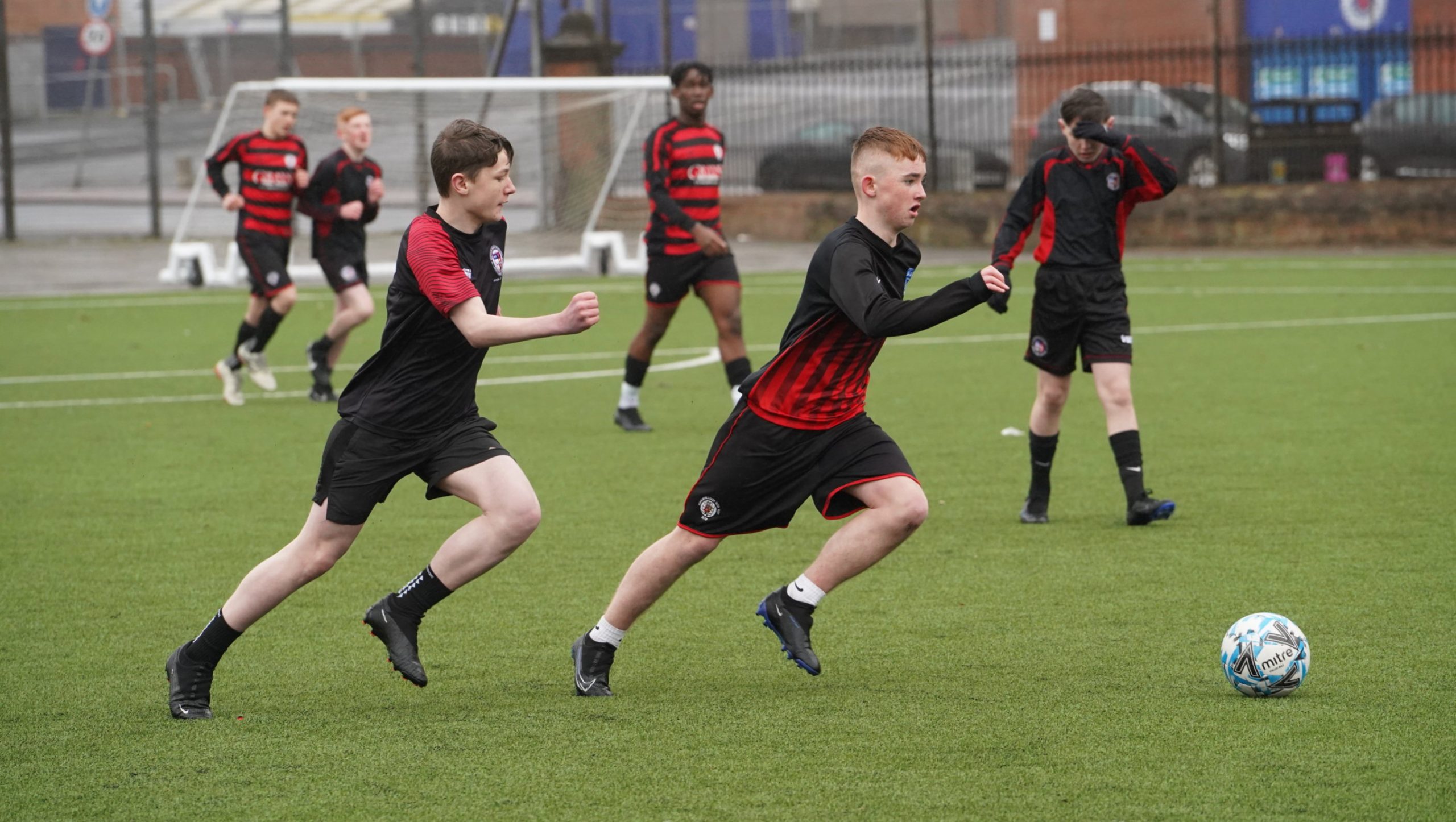 Two male school pupils playing football
