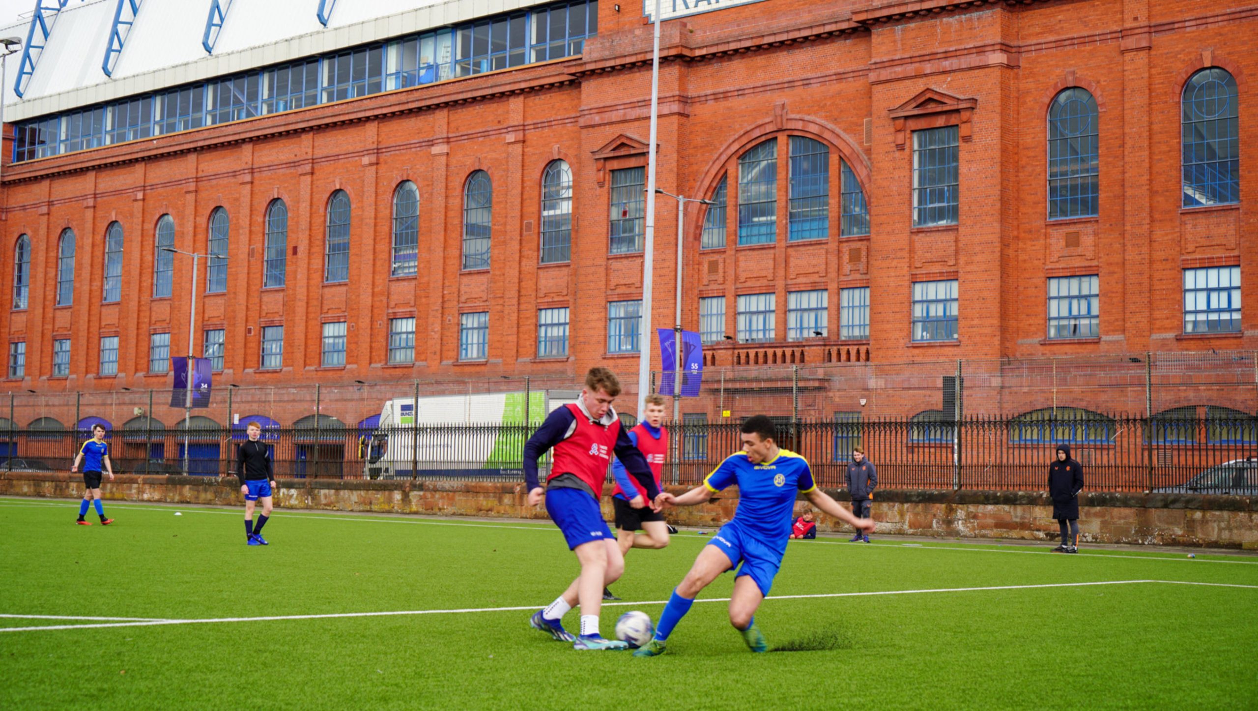 Two young people playing football next to Ibrox