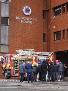 A group of young people standing in front of a fire engine with firefighters