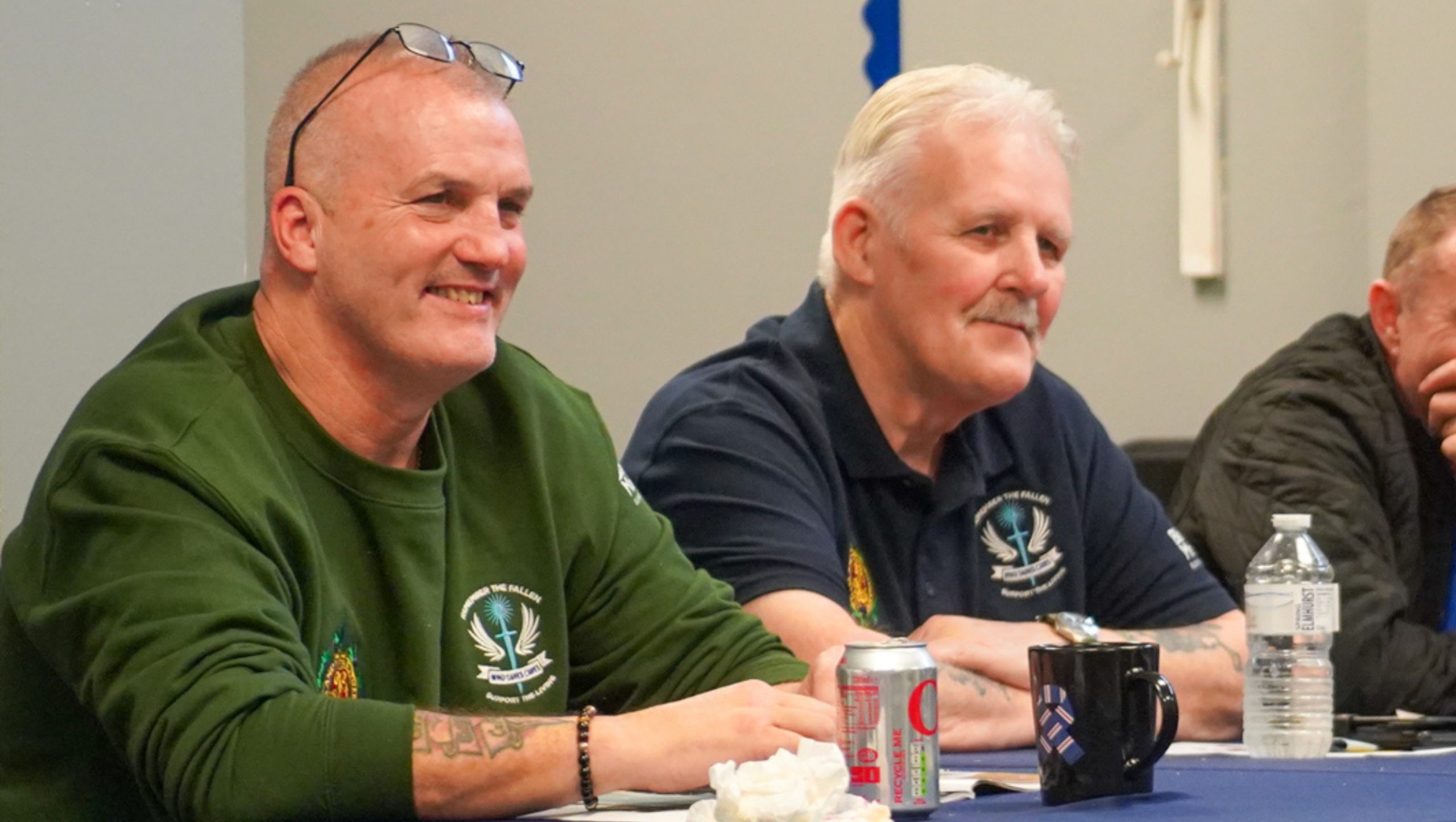 Two veterans attending a support group and smiling will listening to a group discussion