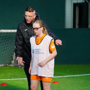 A Visually Impaired Football participant being coached by a Rangers Charity Foundation Community Coach.
