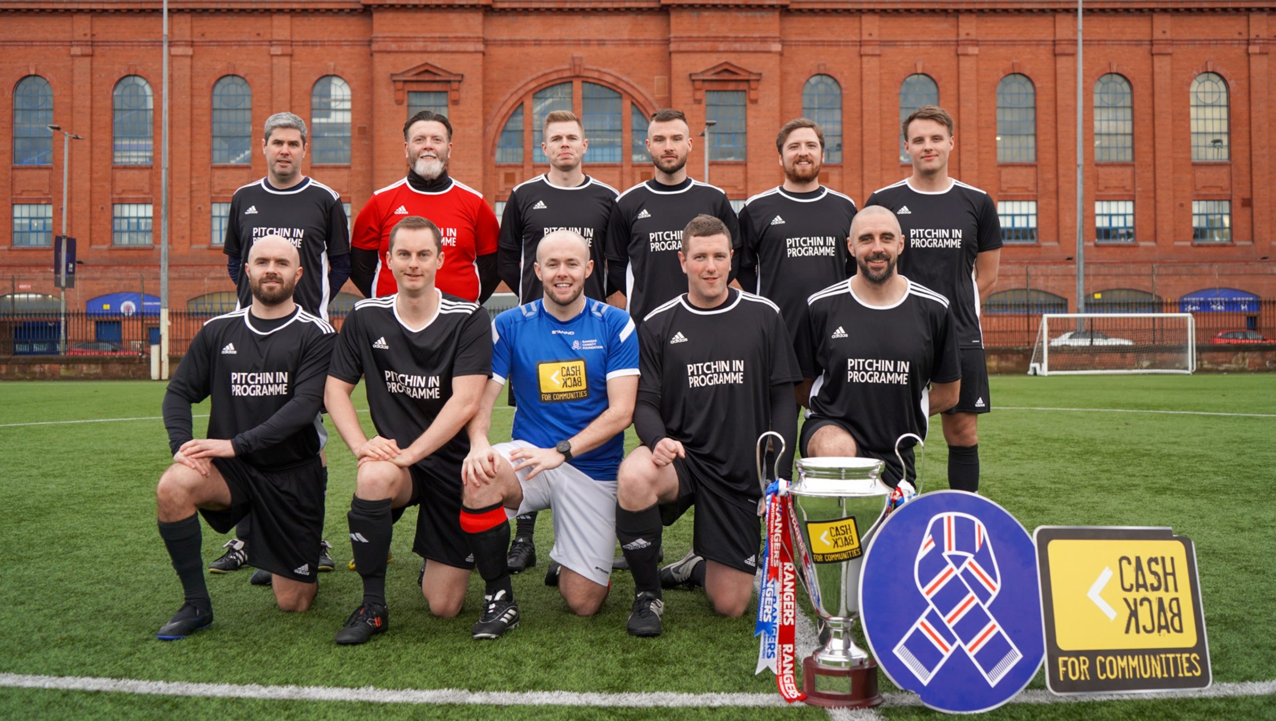 A football team made up of Police Scotland officers posing for a squad photo in front of Ibrox.