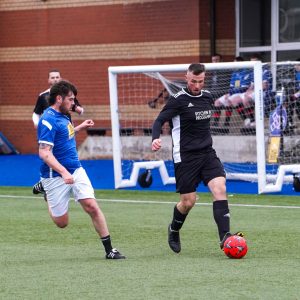 A Police Officer and a Foundation staff member challenging for a loose ball in the CashBack football match.