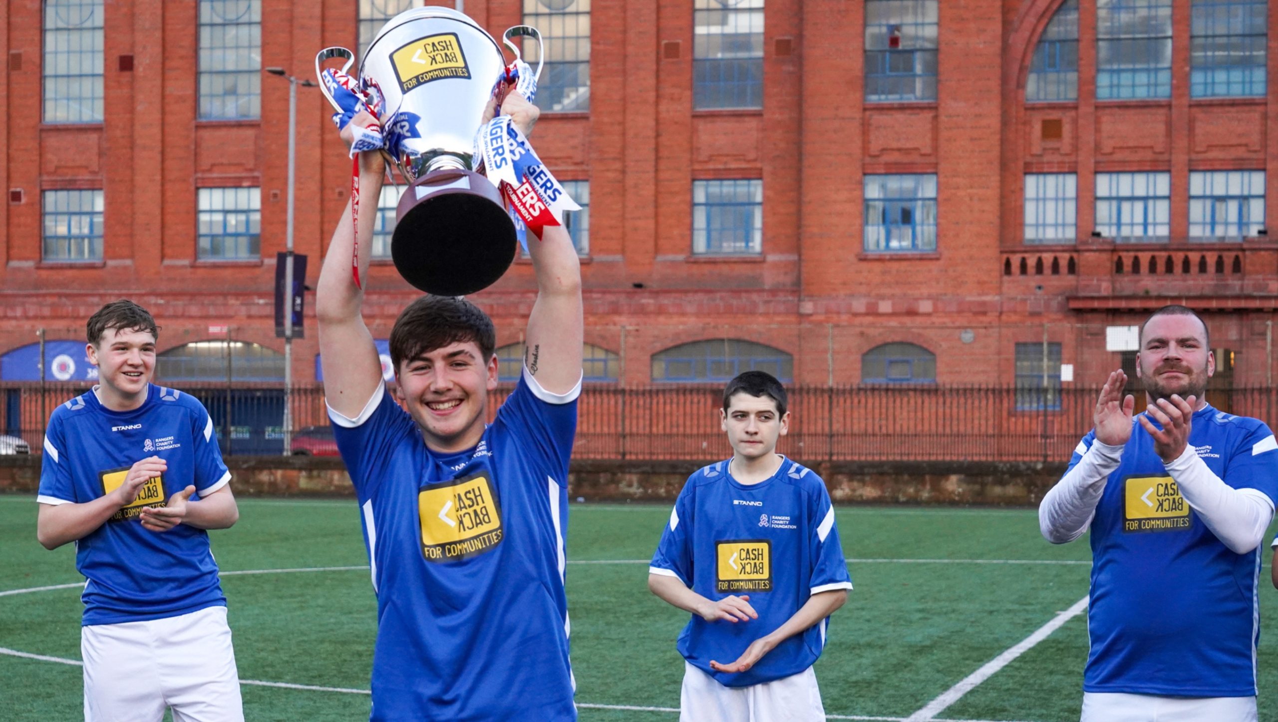 CashBack participants lifting the trophy following victory over Police Scotland in their football match.