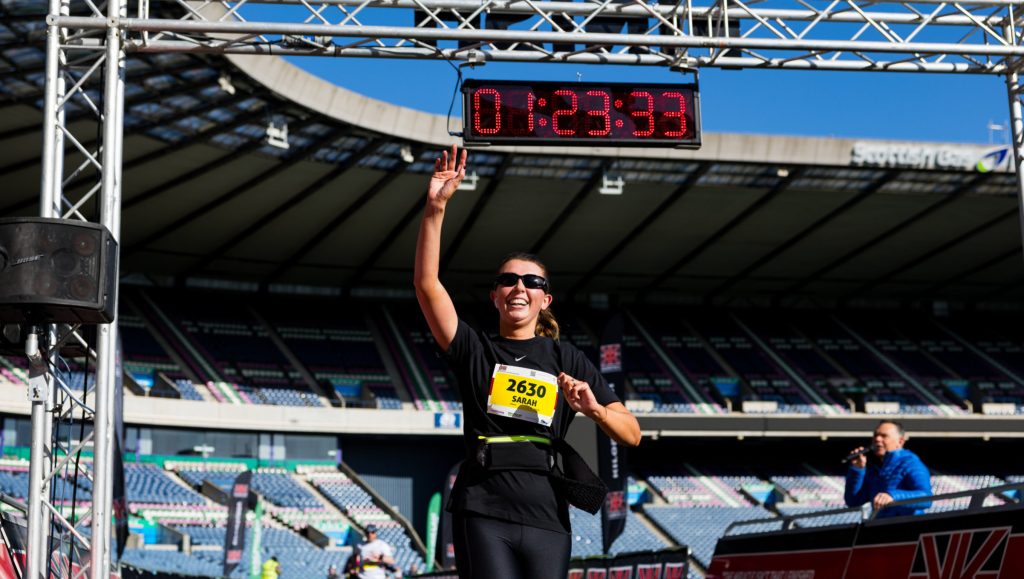 person running across a finish line with arm raised in triumph