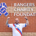 man in charity running top outside ibrox community complex