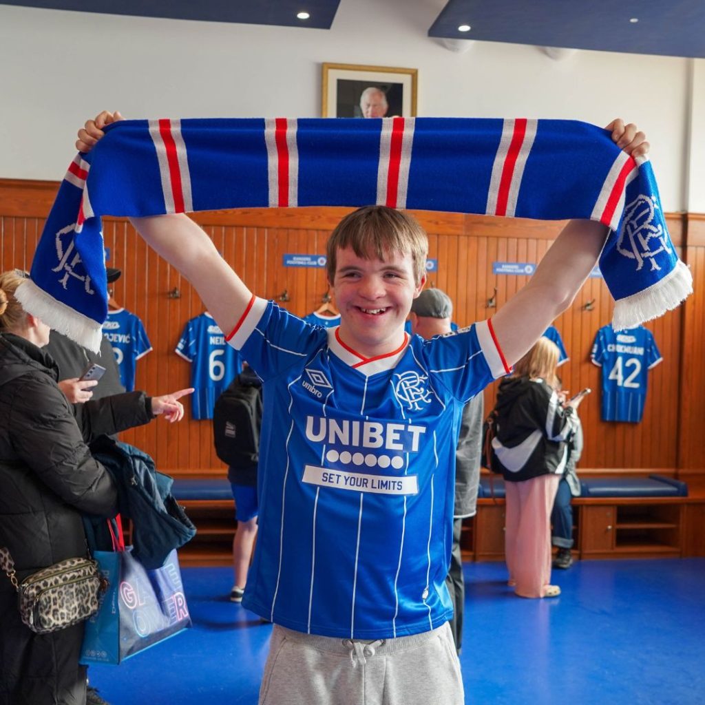 boy smiling in dressing room with rangers scarf